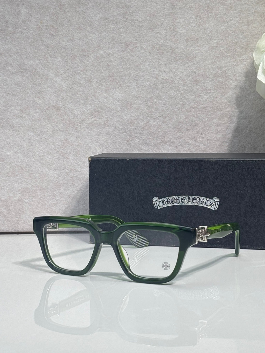 Green and silver eyeglasses with square frames and clear lenses