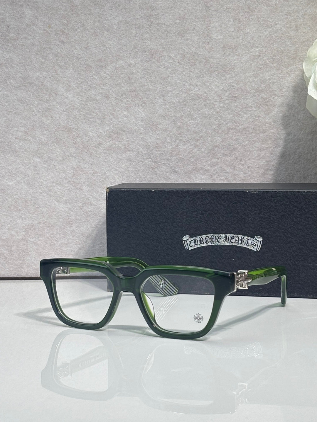Green and silver eyeglasses with square frames and clear lenses