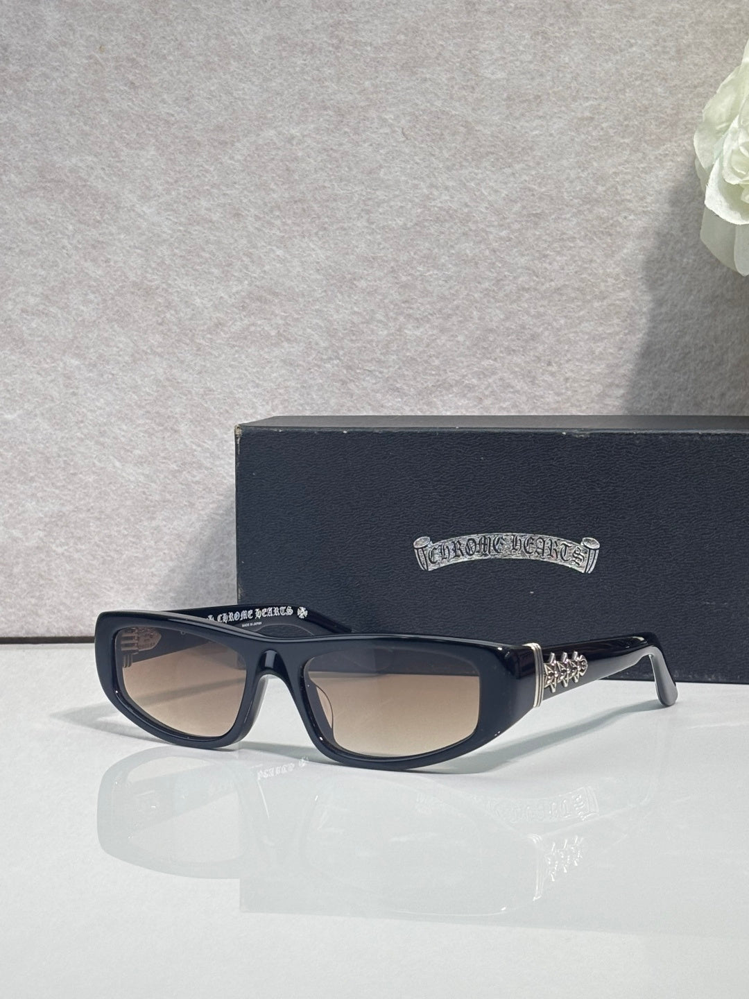 Chrome glasses with black frames and neutral-tinted lenses, with star-style metal accents.