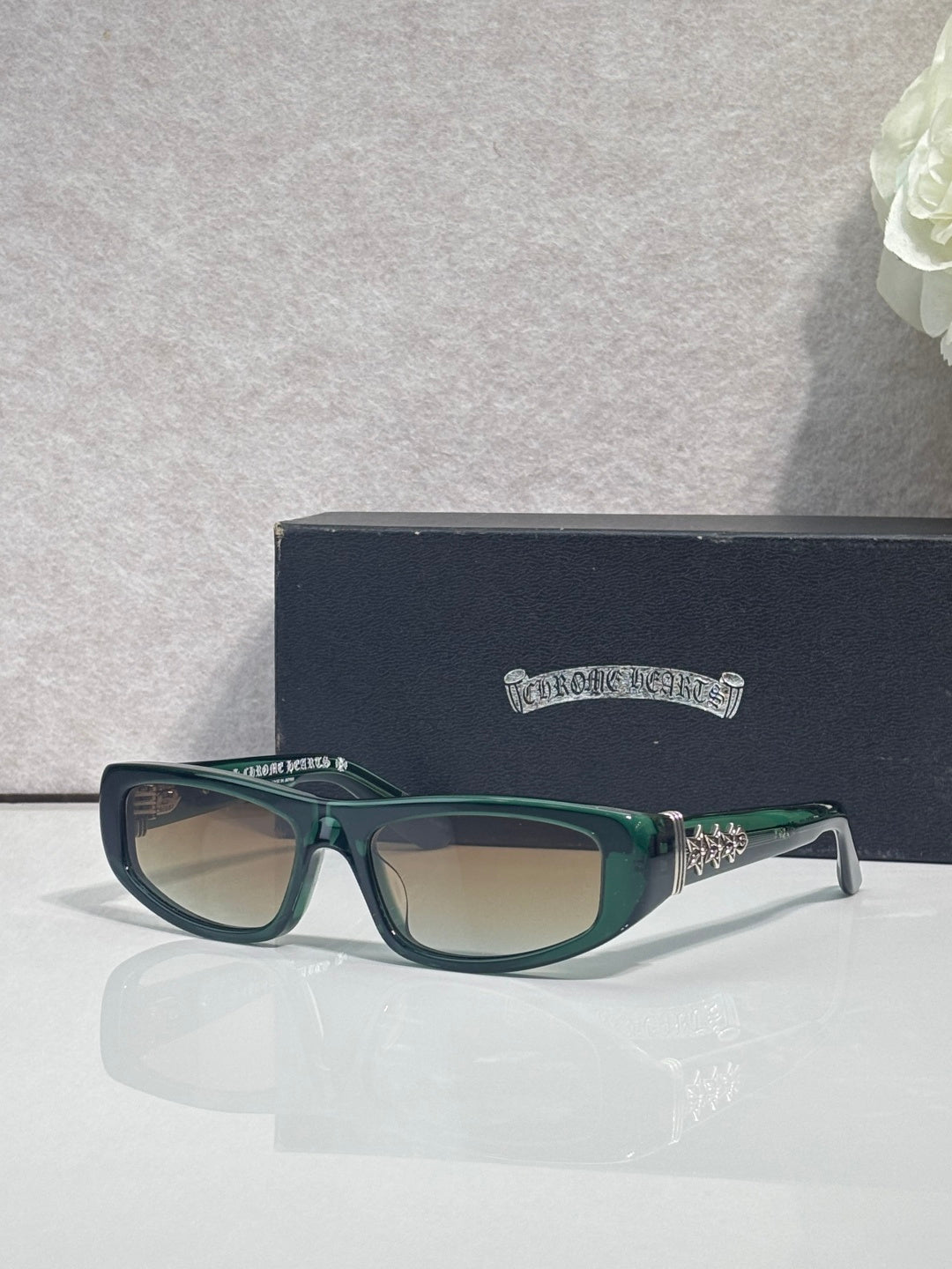 Chrome glasses with teal frames and neutral-tinted lenses, with star-shaped metal accents.
