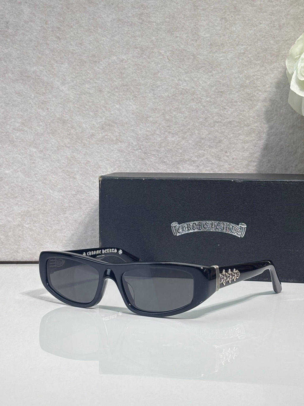 Chrome glasses with dark frames and neutral-tinted lenses, featuring star metal details on temples.