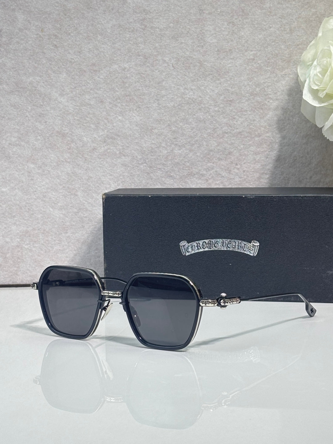 Chrome-rim square sunglasses with dark lenses and black frame, clear temple