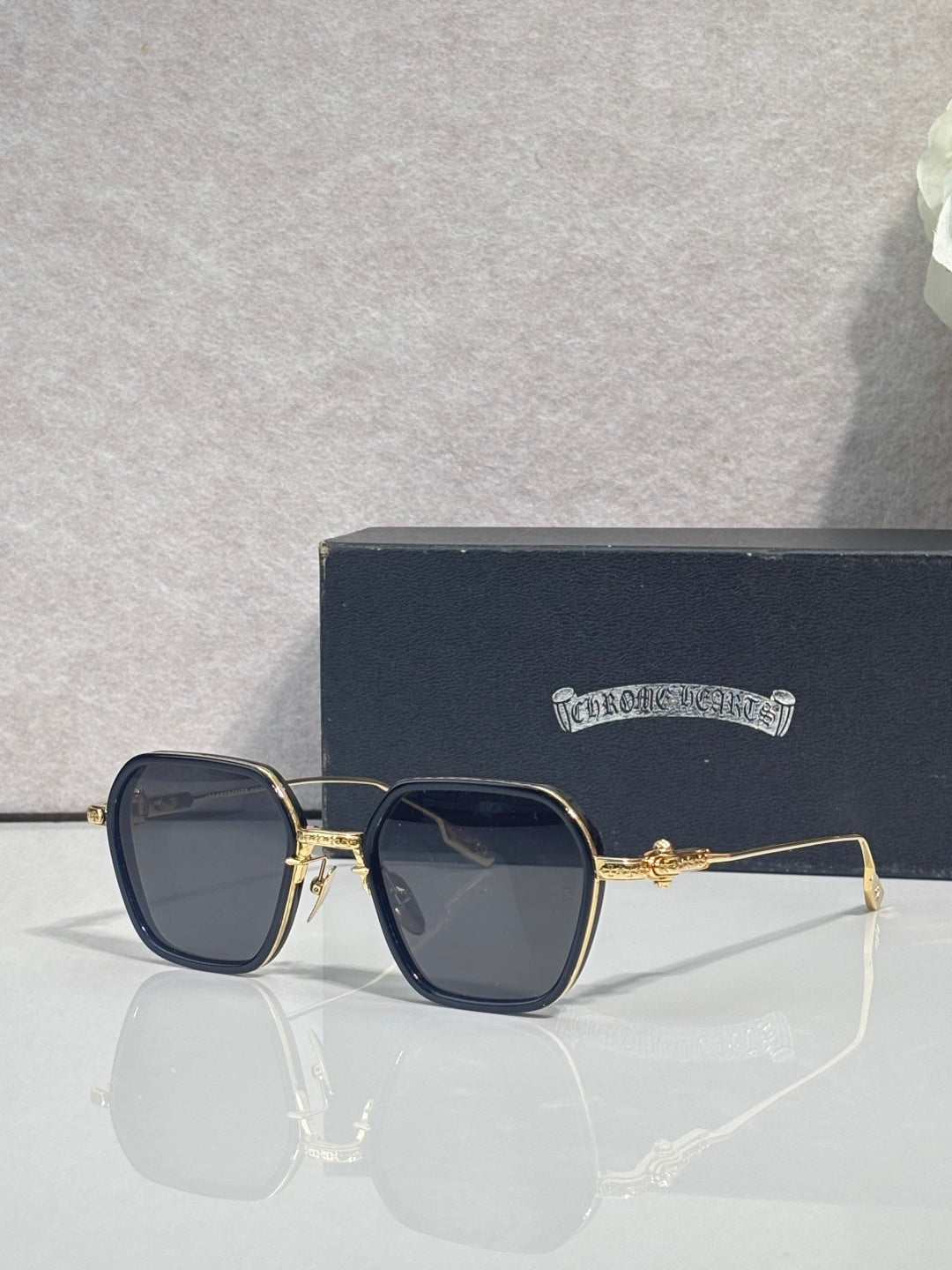 Gold-rim square sunglasses with dark lenses and navy frame accents, clear temple