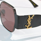 Black sunglasses with rosy tinted lenses and gold YSL-style side logo