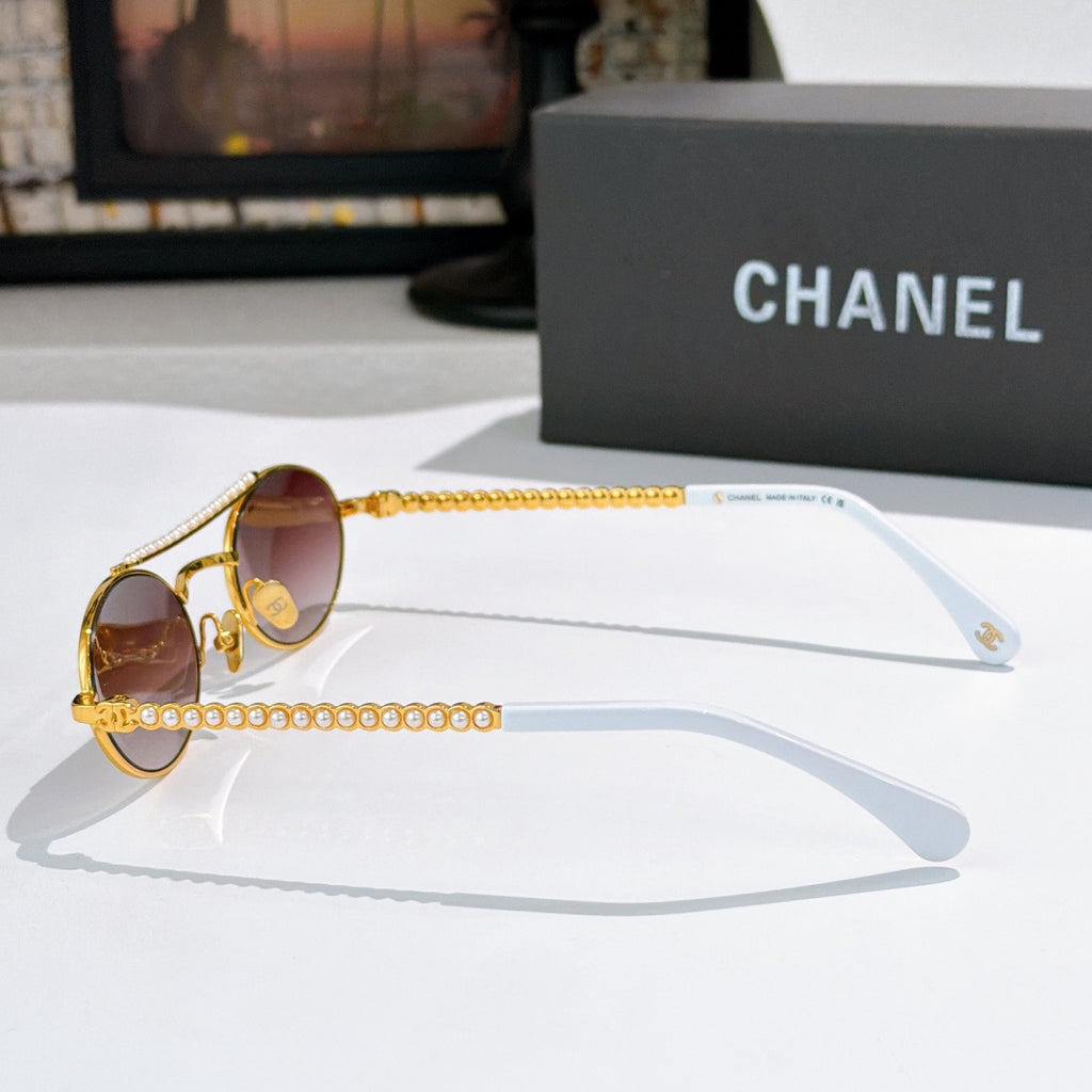 Gold round sunglasses side view with pink lenses and pearl chain temple detail