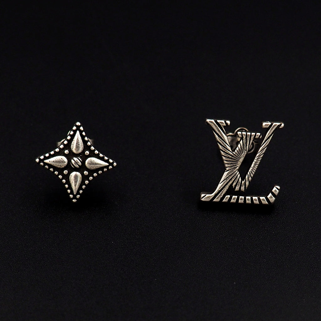 Louis Vuitton accessories: silver star and LV monogram stud earrings on dark background