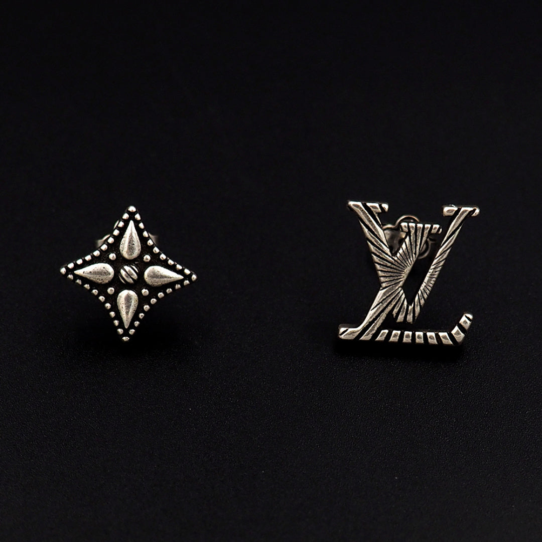 Louis Vuitton accessories: silver star and LV monogram stud earrings on dark background