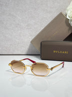 Sunglasses with light tan lenses and gold metal frame, red acetate center bar
