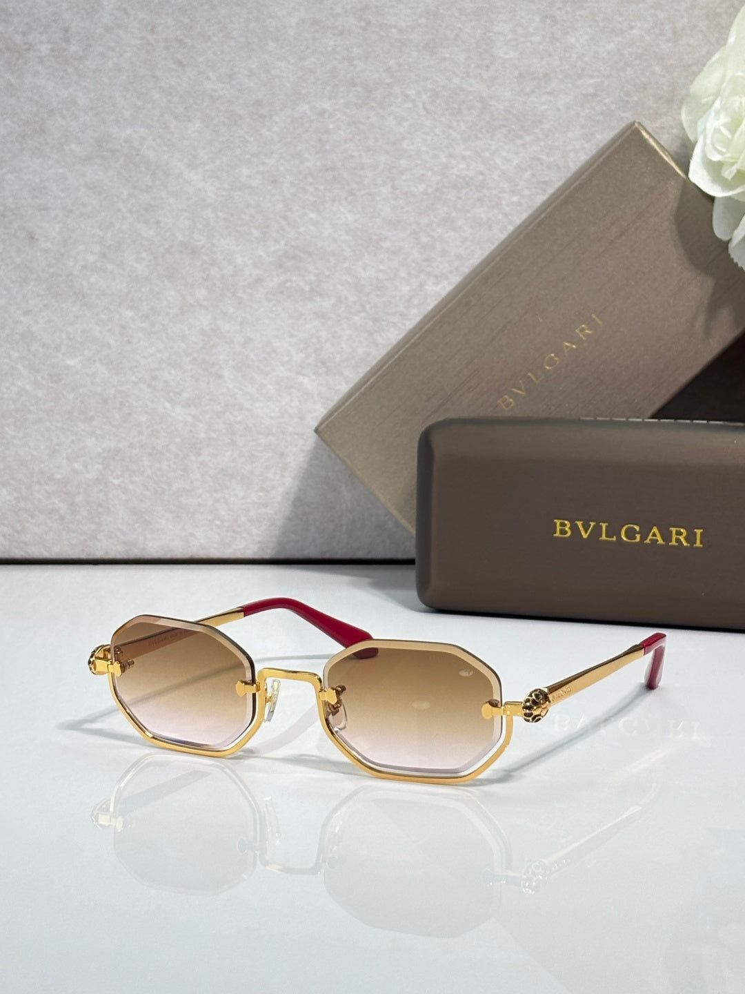 Sunglasses with light tan lenses and gold metal frame, red acetate center bar