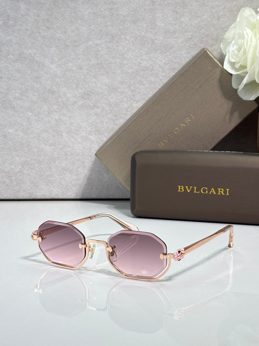 Sunglasses with pink tinted lenses and rose-gold metal frame, gold-tone accents