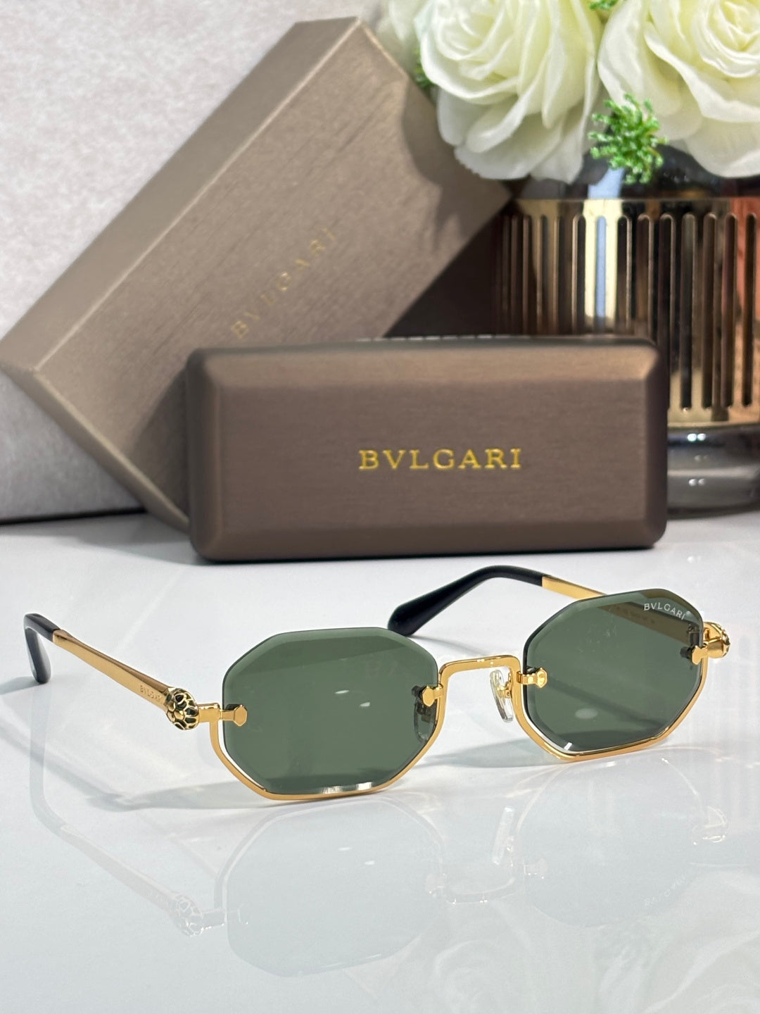 Sunglasses with deep green lenses and gold metal frame, black temple arms