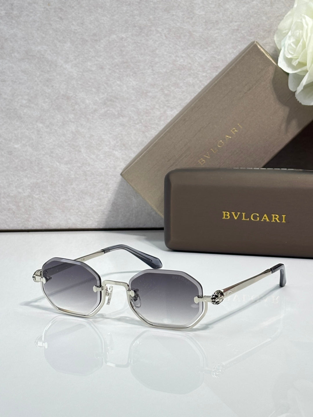 Sunglasses with dark gray lenses and silver metal frame, angular brow