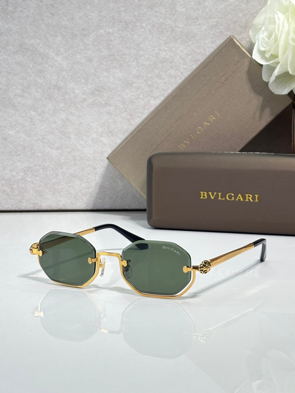 Sunglasses with green tinted lenses and dark frame, gold-tone temple ornaments