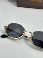 Octagonal sunglasses with gold frame, dark lenses, and black temple
