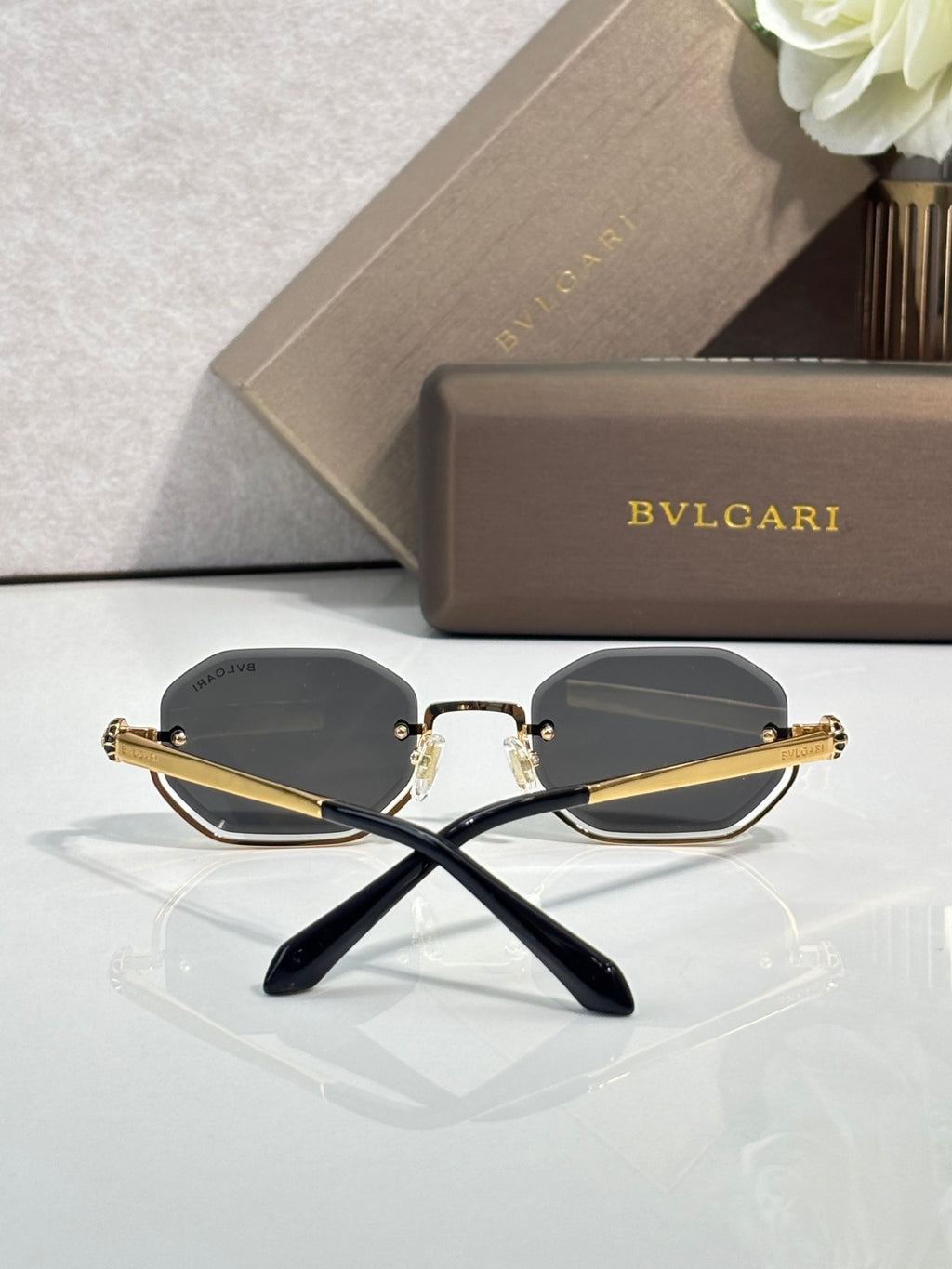 Octagonal sunglasses with gold-tone frame and dark lenses, crossed temple view