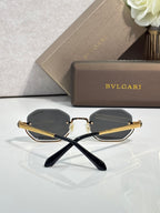 Octagonal sunglasses with gold-tone frame and dark lenses, crossed temple view