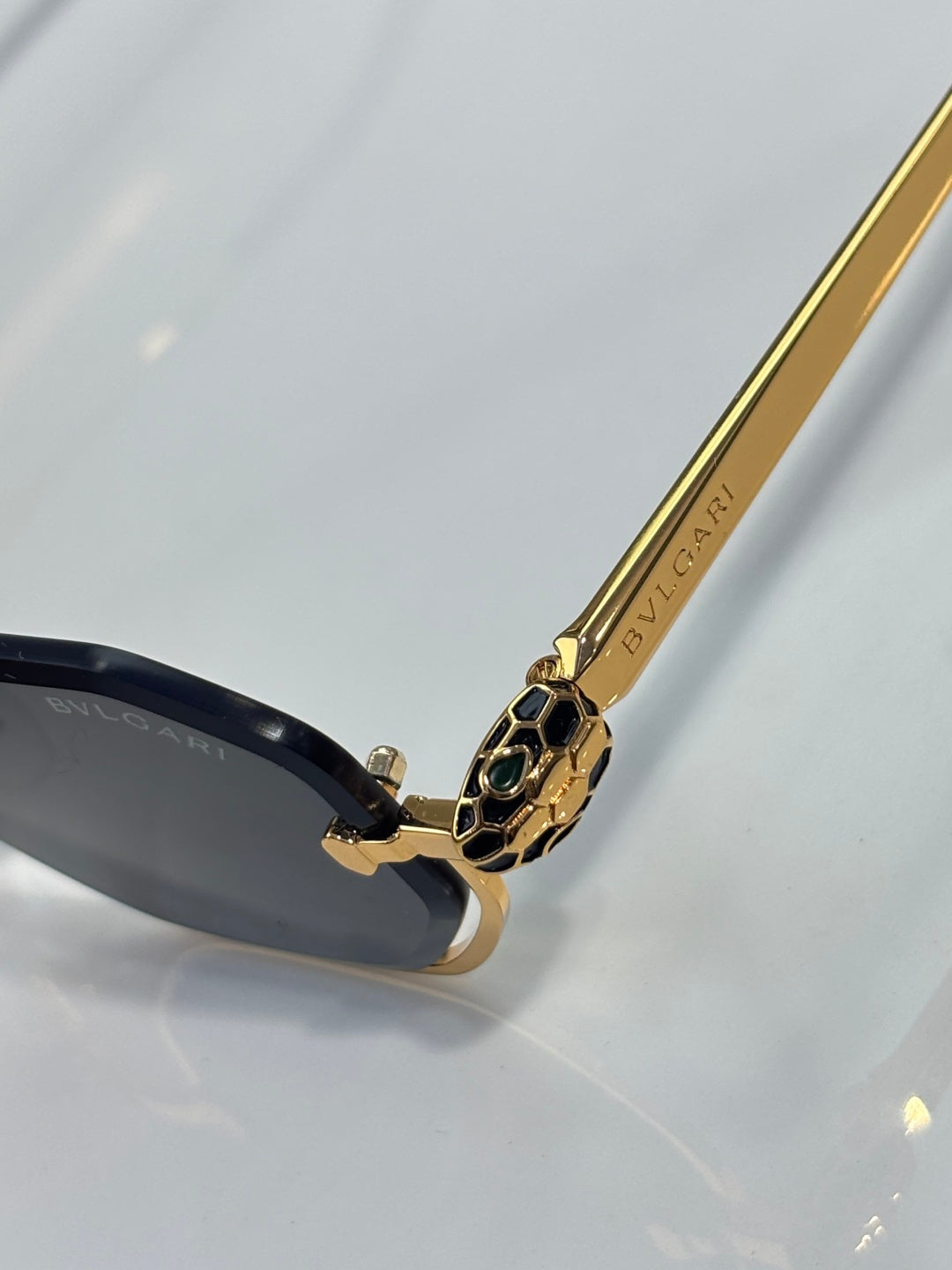 Gold temple arm with printed branding and black lens frame