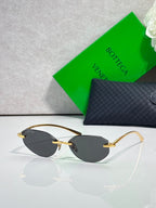 Bottega Veneta sunglasses with dark lenses and gold metal frame, oval pilot style