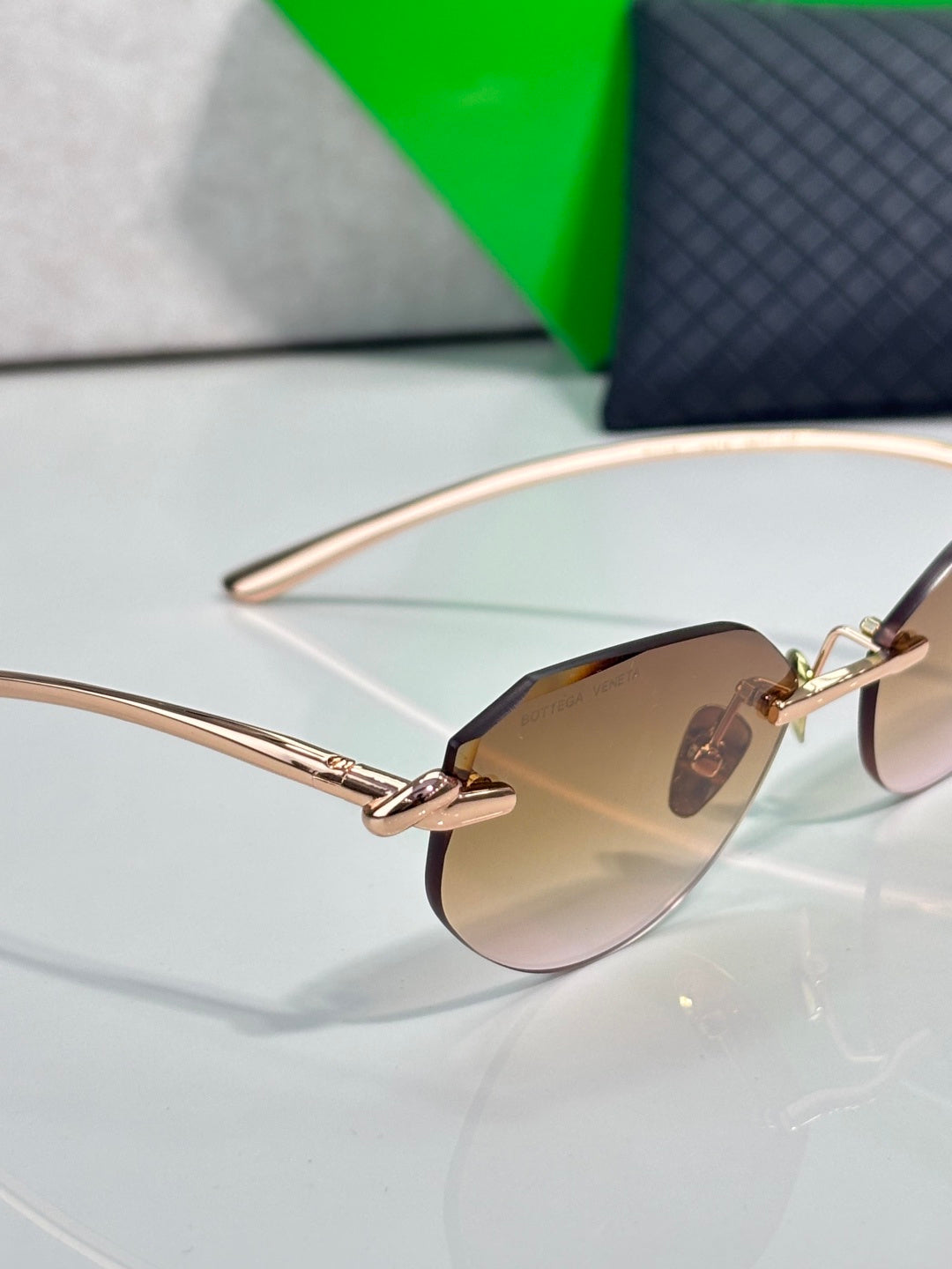 Bottega Veneta sunglasses close-up with amber-brown lenses and rose-gold frame