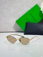 Bottega Veneta sunglasses with warm brown lenses and gold frame, oval pilot design