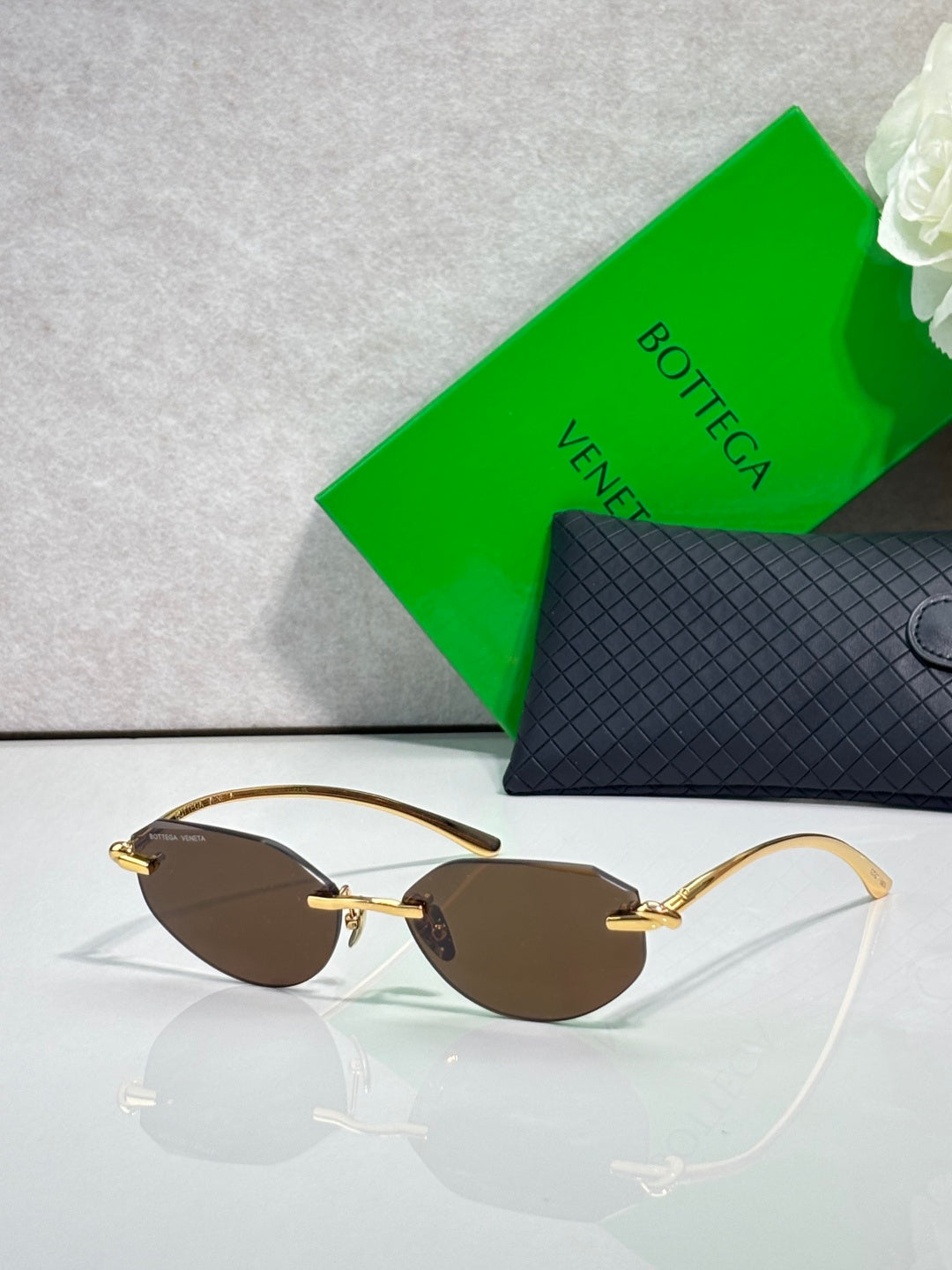 Bottega Veneta sunglasses with brown lenses and tan-gold frame, oval pilot style