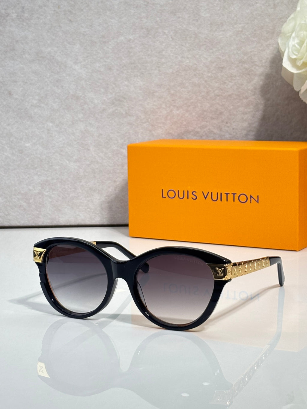 Sunglasses with black round frames, gold-tone temple detailing, and dark lenses