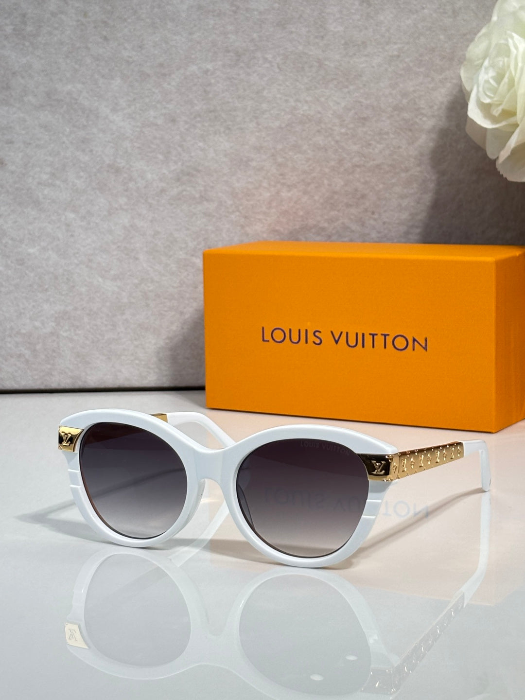 Sunglasses with white round frames, gold-tone accents, and tinted lenses