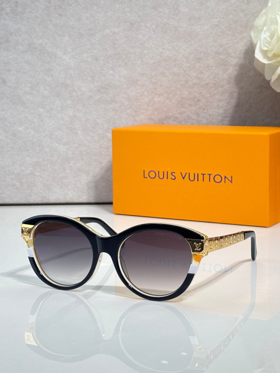 Sunglasses with black round frames, gold-tone accents, and tinted lenses