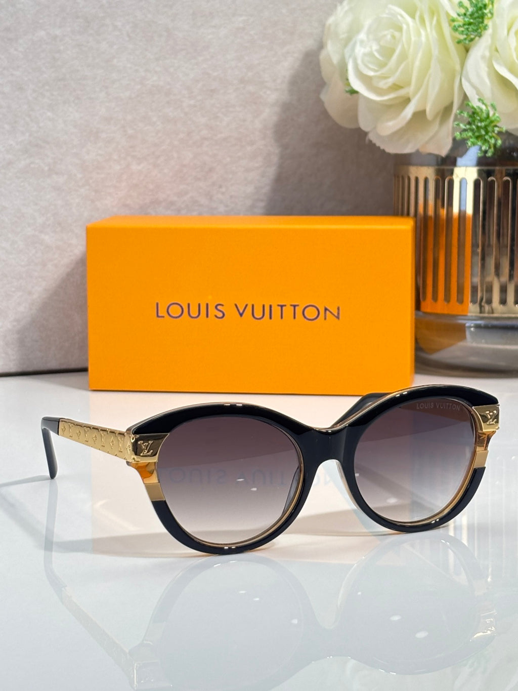 Sunglasses with black round frames, gold-tone temple accents, and dark tinted lenses