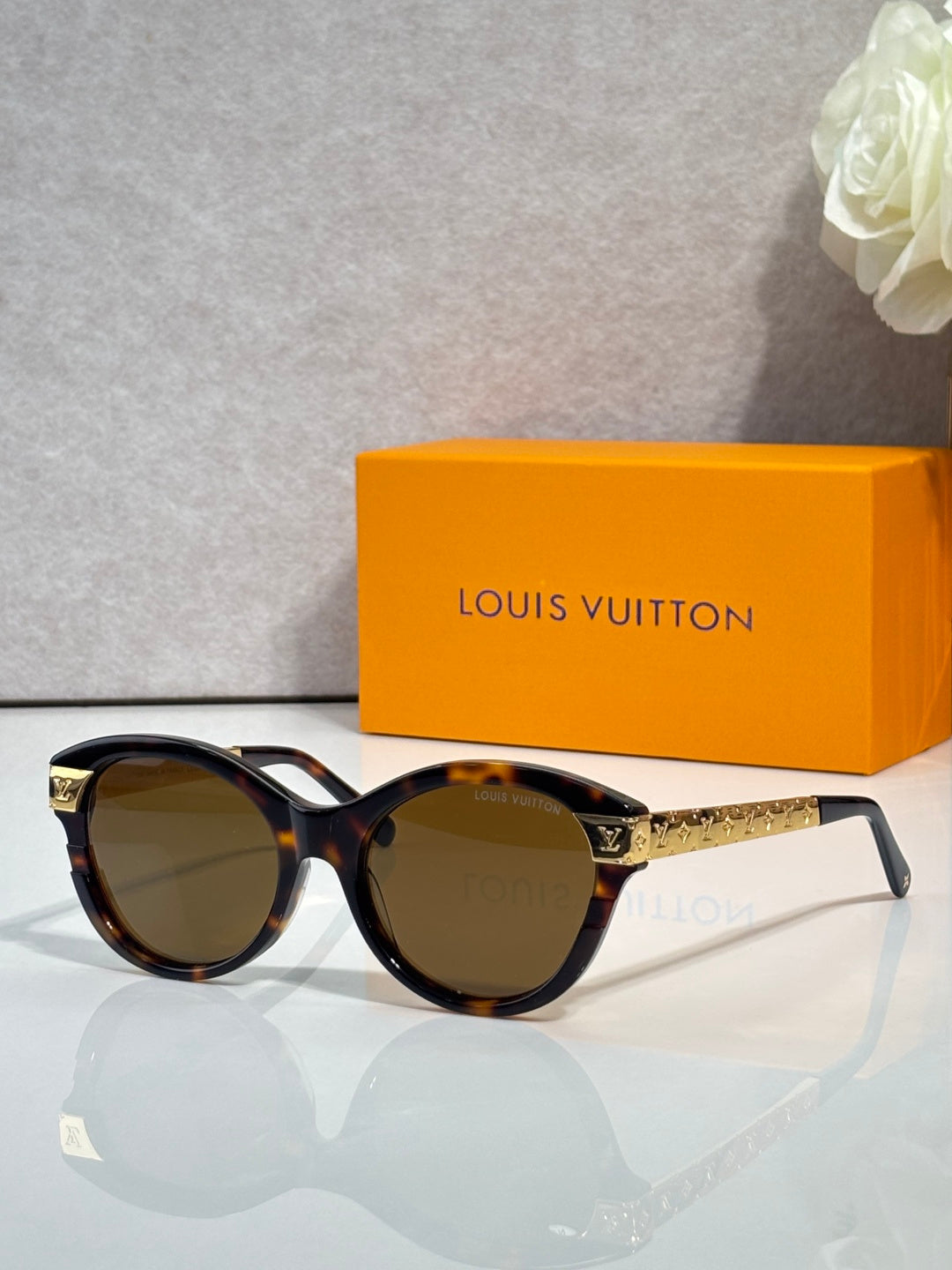 Sunglasses with tortoiseshell round frames, gold-tone temple accents, and dark lenses