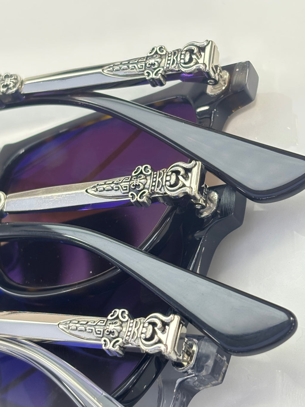 Chrome glasses close-up of dark frames and purple-blue lenses, ornate chrome hinge