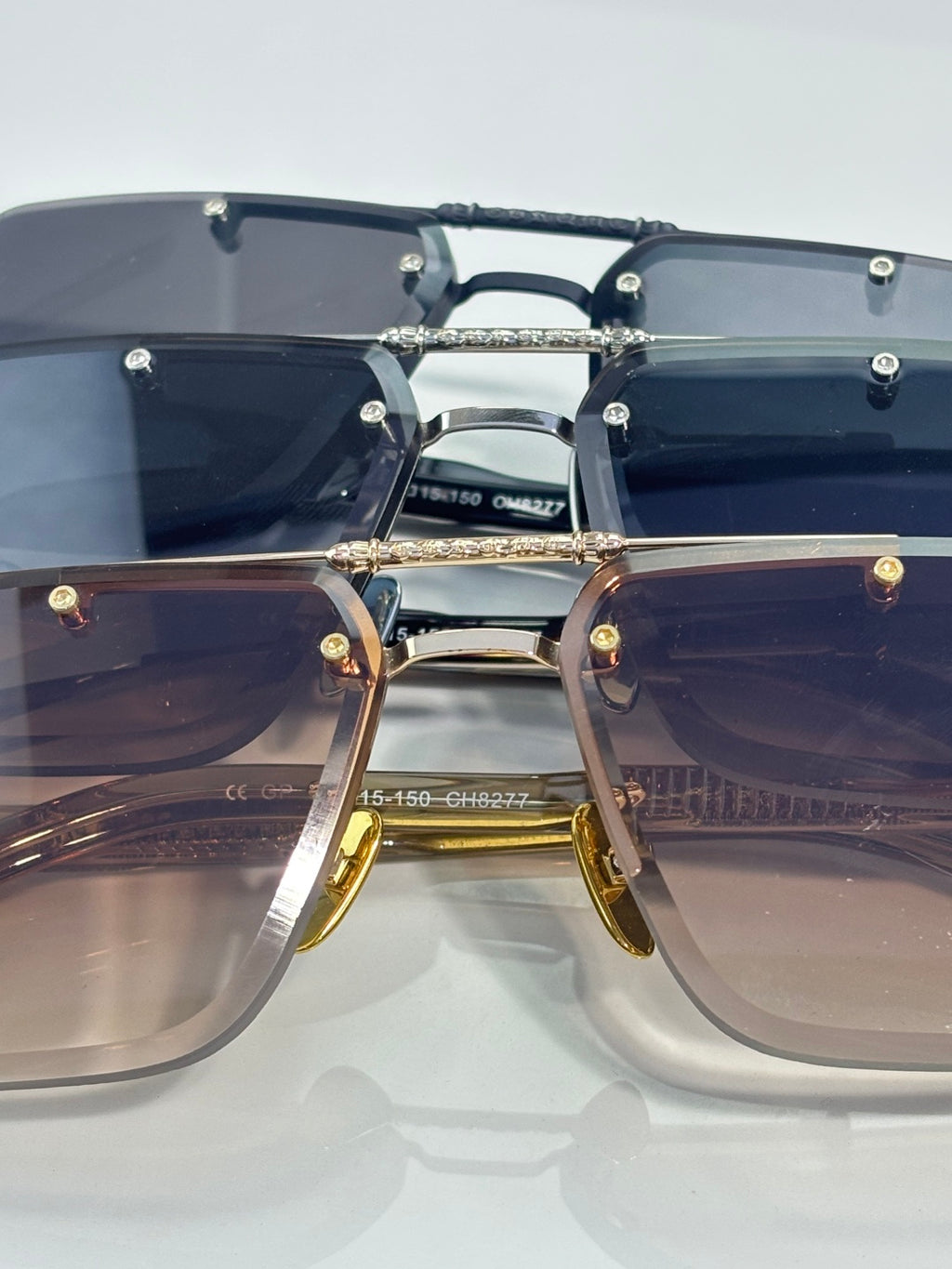 Pair of sunglasses with dark and brown-tinted lenses, mixed metal frames, and bridge logo