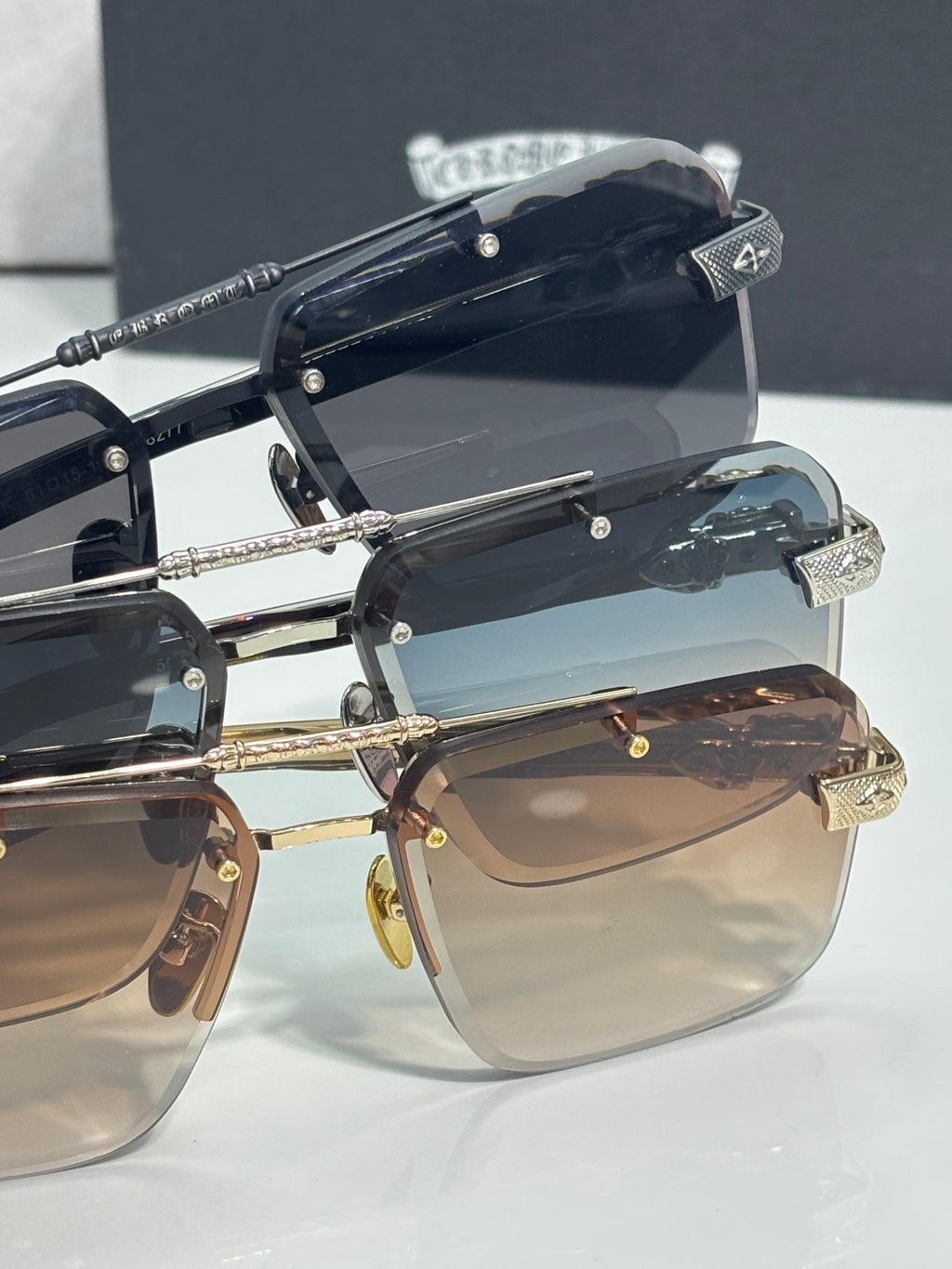 Stacked sunglasses view with black frames, tinted lenses, and gold-tone details