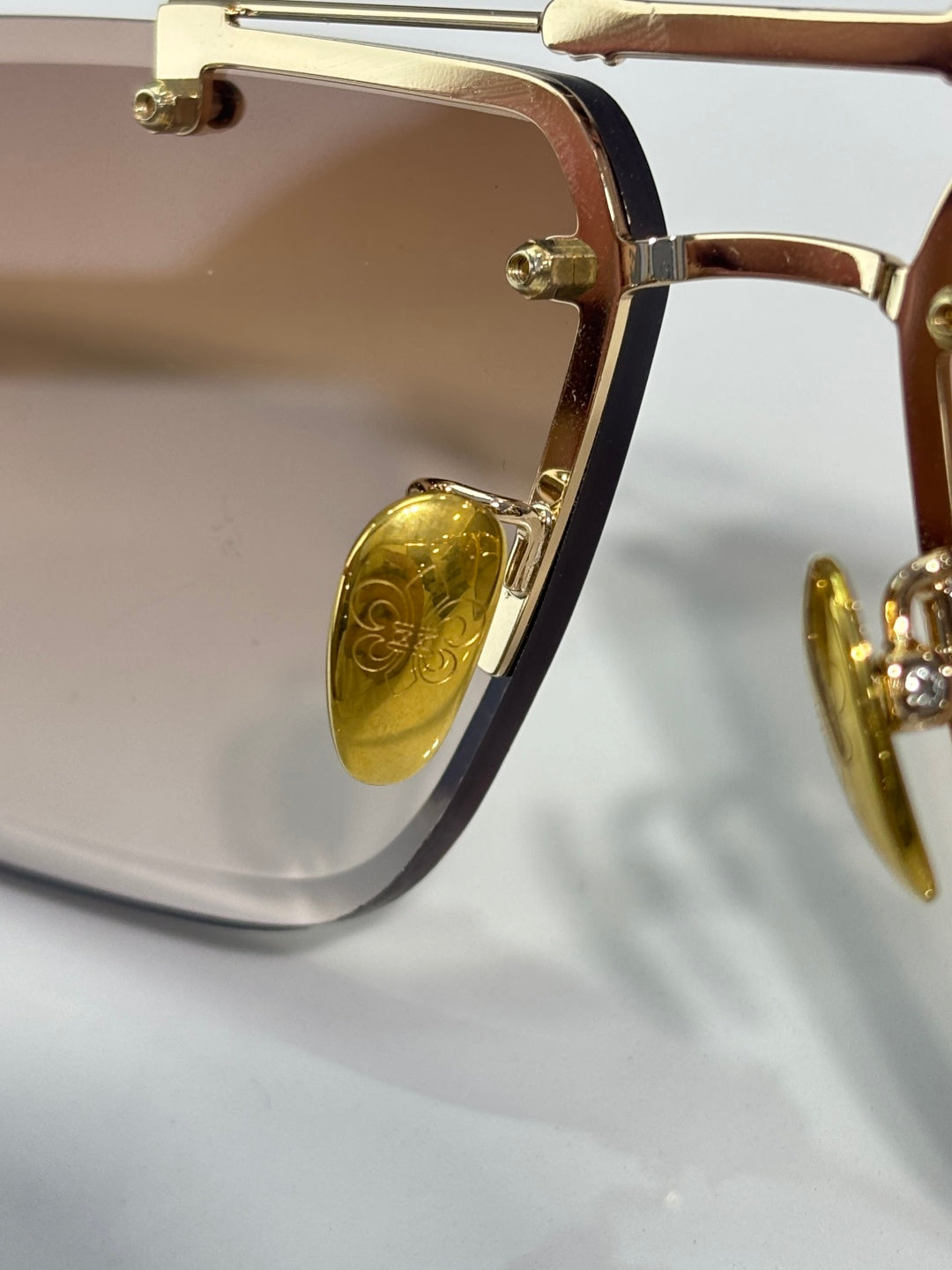 Close-up of gold-tone sunglasses frame with light-tinted lenses and hinge detail