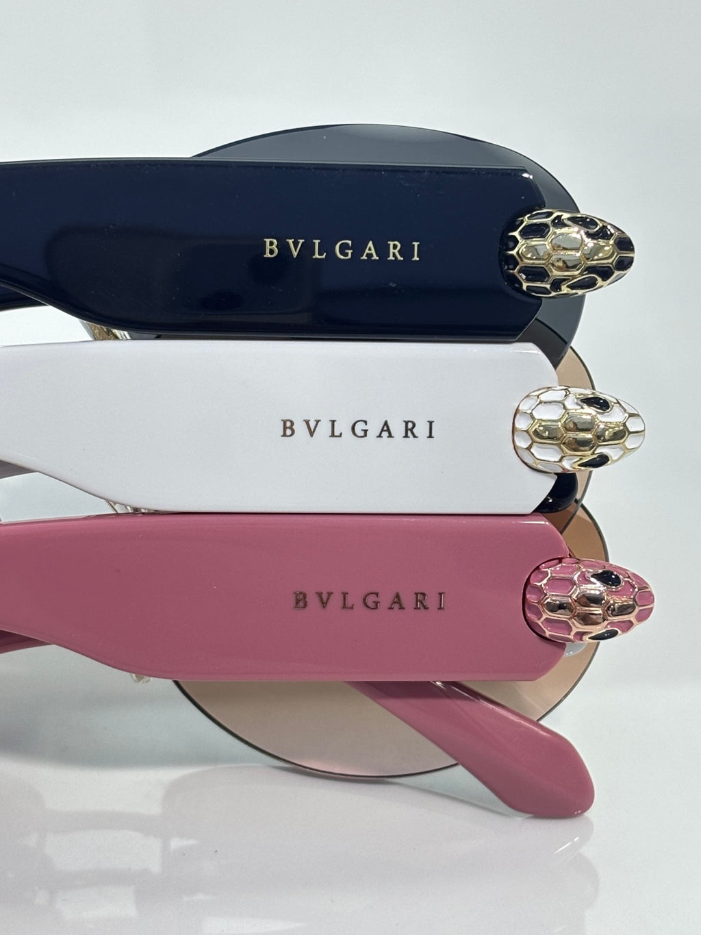 Sunglasses close-up with dark blue, white, and pink temples plus gold-tone hinges