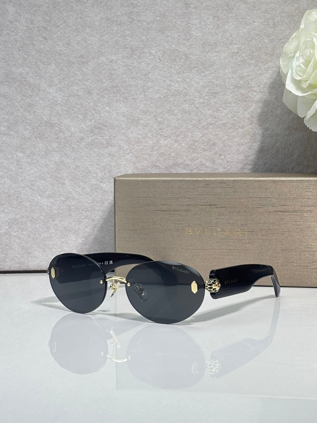 Sunglasses with dark lenses, navy temples, and gold-tone embellished hinge