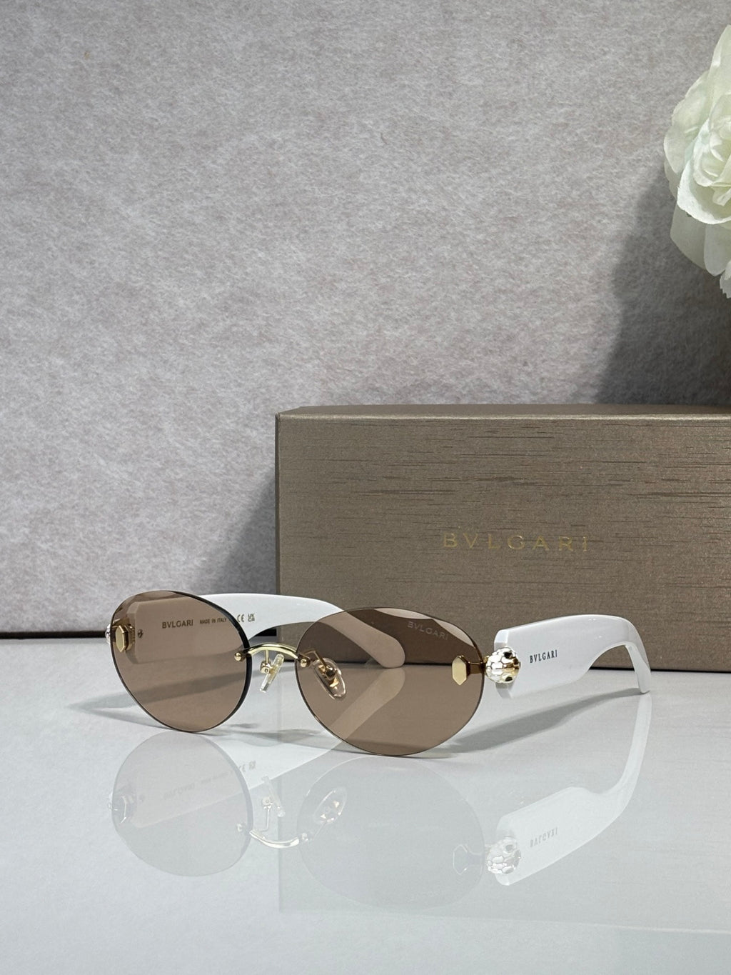 Sunglasses with brown gradient lenses, gold-tone frame, and white temples