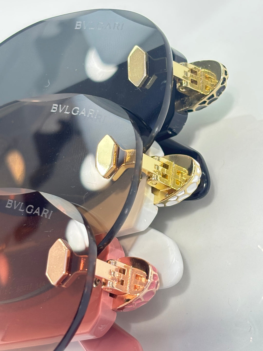 Sunglasses close-up with dark lenses and gold-tone studded hinges in mixed colors