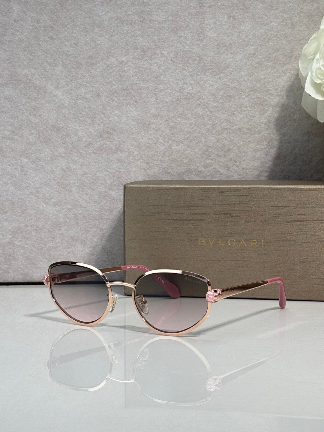 Rose and gold-tone oval sunglasses with dark tinted lenses and pink temples