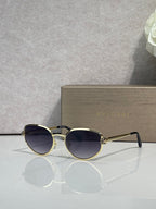 Gold-tone round sunglasses with dark navy tinted lenses and thin metal temples
