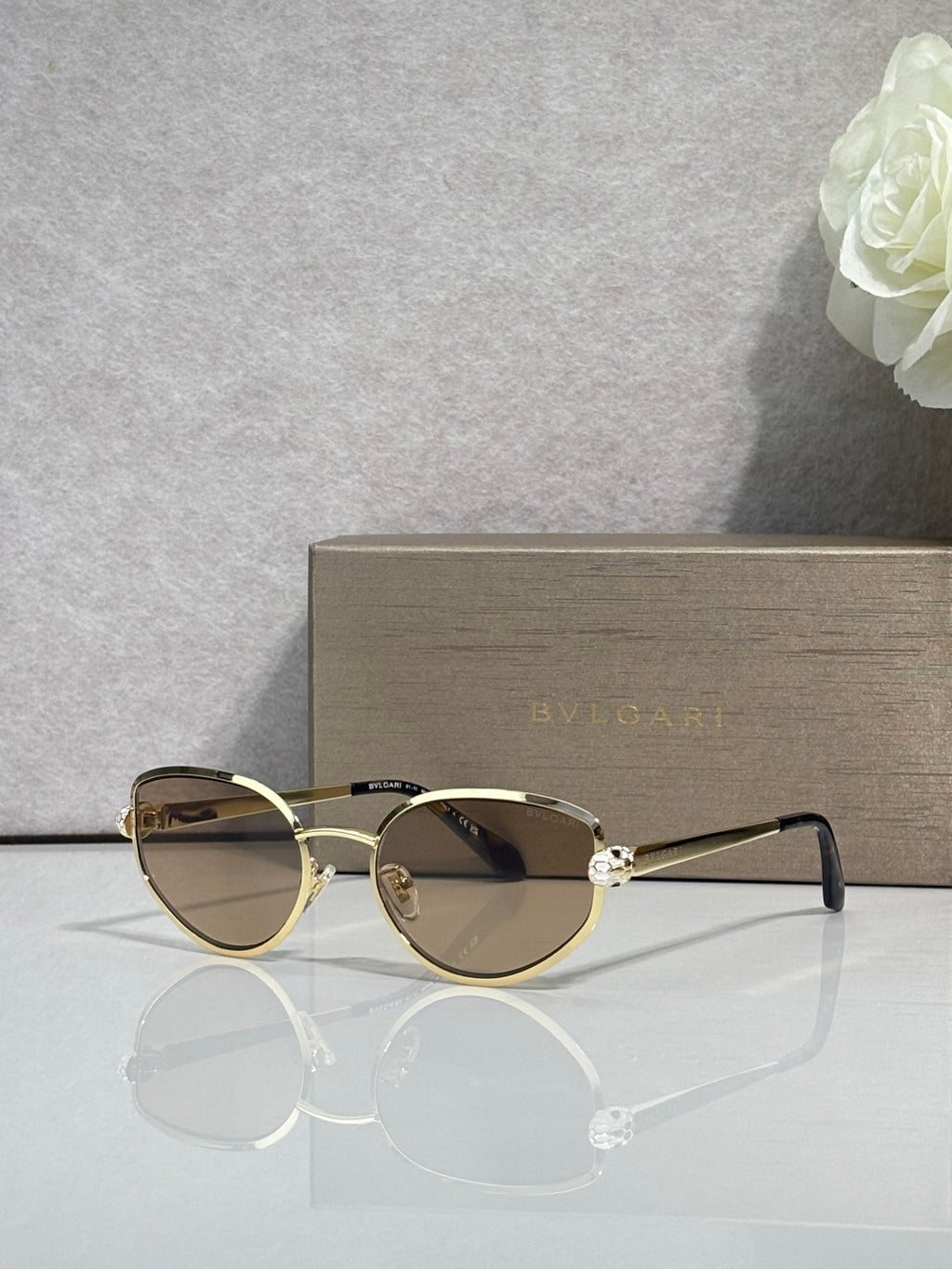 Gold-tone oval sunglasses with tinted lenses and slender metal arms with gold tips