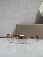 Gold-tone oval sunglasses with dark tinted lenses and metal bridge detail