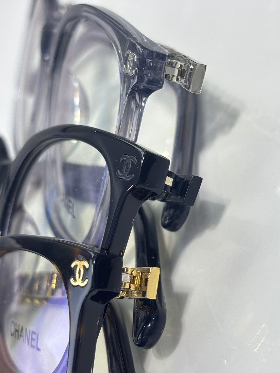 Eyeglasses side view with clear-to-dark blue frame and gold logo clasp hardware.
