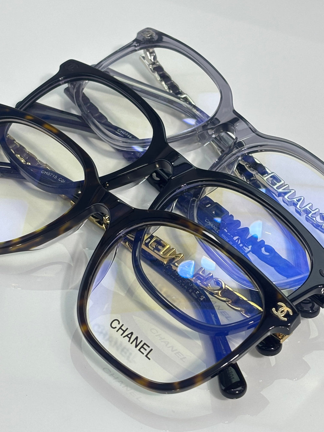 Eyeglasses top view with dark blue frames, blue lenses, and CHANEL branding on arms.