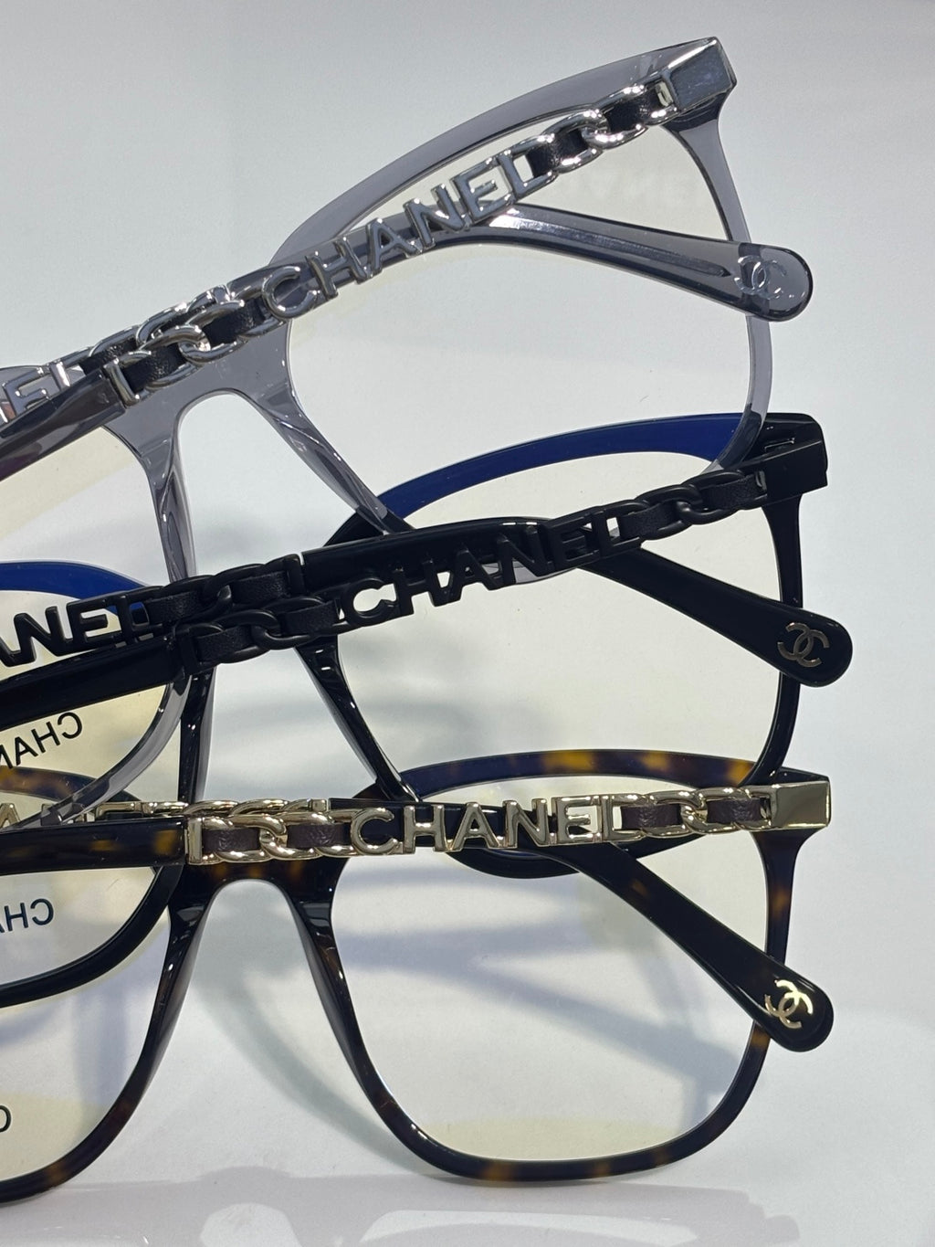 Eyeglasses close-up of dark blue chain strap with gold CHANEL letters and temple caps.
