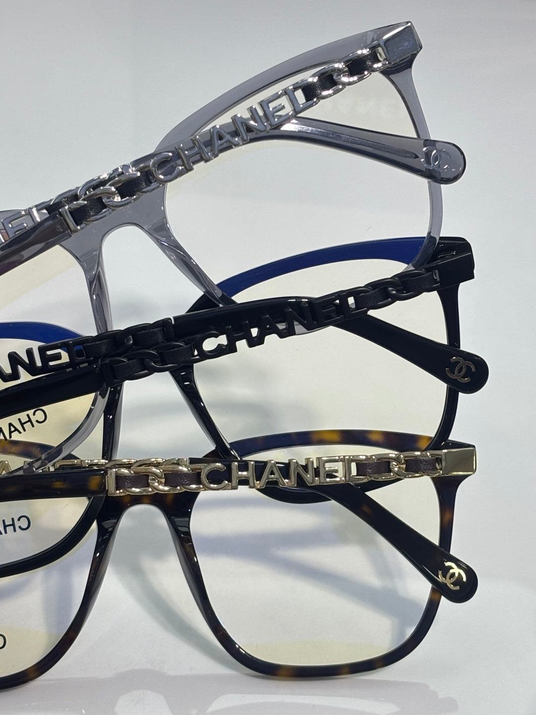 Eyeglasses close-up of dark blue chain strap with gold CHANEL letters and temple caps.