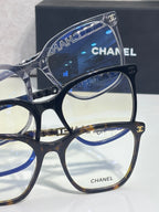 Eyeglasses close-up showing blue-tinted lens and gold CHANEL logo on frame front.