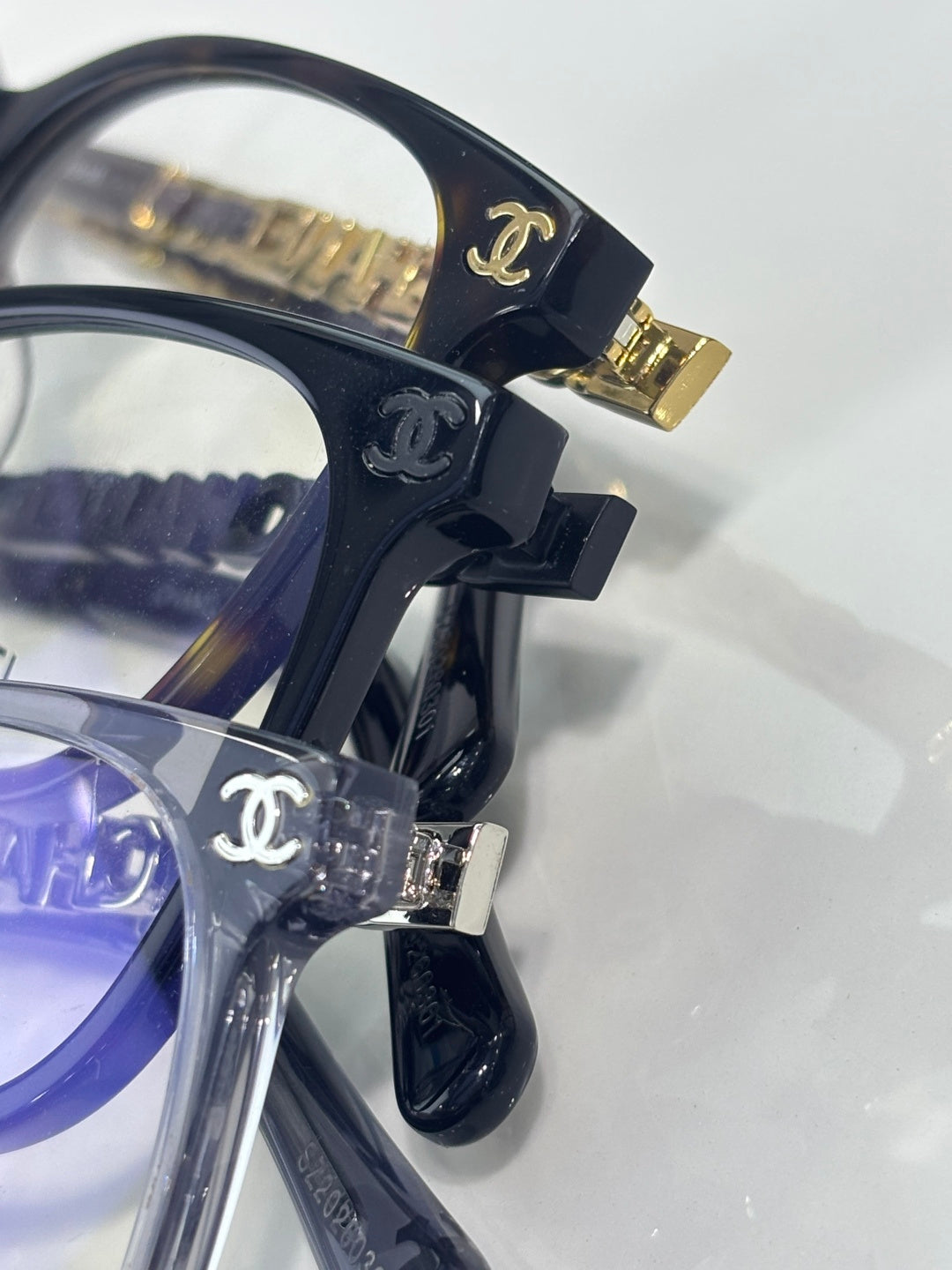 Chanel glasses close-up of dark hinges and gold logo emblem on temple