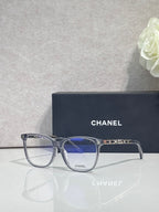Chanel glasses with dark frames and blue-tinted lenses, logo on the temples