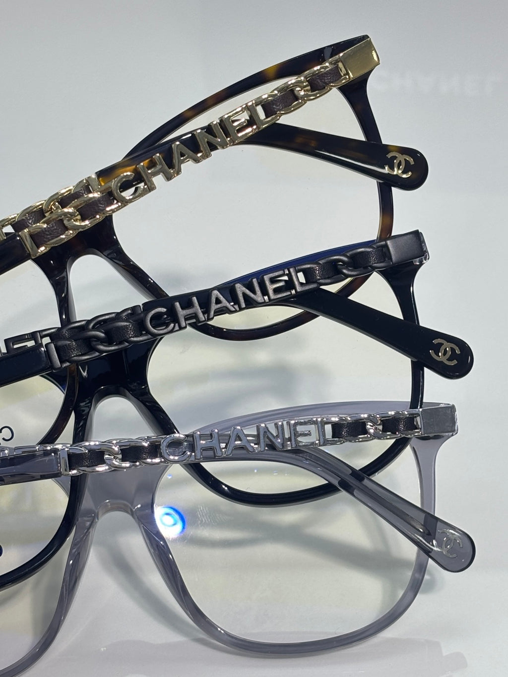 Chanel glasses close-up showing dark frames with gold chain-printed temple trim